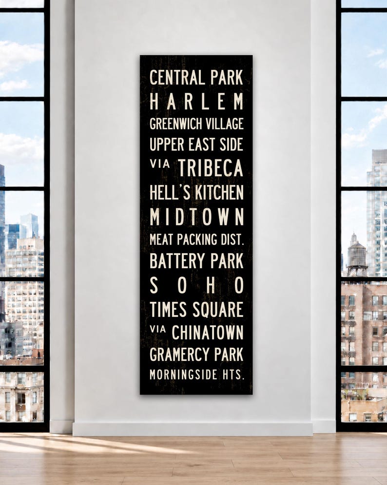 May include: A tall, rectangular black wall sign featuring white text listing New York City neighborhoods including Central Park, Harlem, Greenwich Village, Upper East Side, Tribeca, Hell&rsquo;s Kitchen, Midtown, Meat Packing Dist., Battery Park, Soho, Times Square, Chinatown, Gramercy Park, and Morningside Hts.