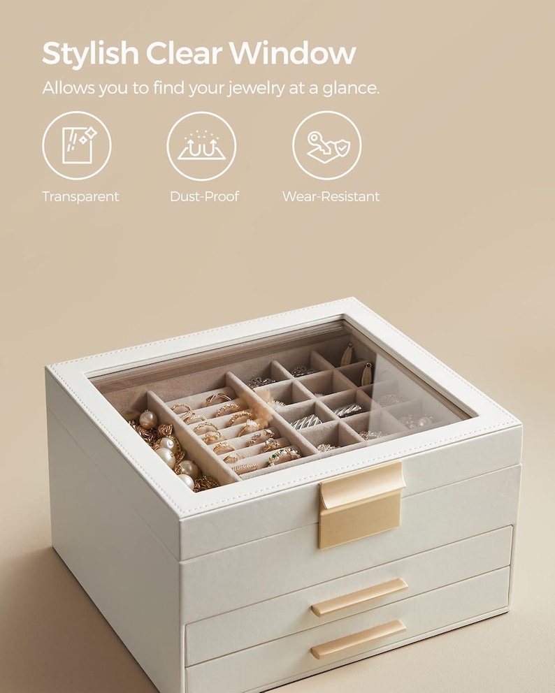 May include: A white jewelry storage box with a clear window, featuring multiple compartments. The box has a gold-coloured clasp and drawer pulls. Text on the image reads "Stylish Clear Window" and "Allows you to find your jewelry at a glance."