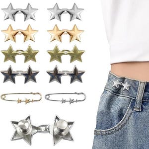 May include: A collection of star-shaped metal accessories in silver, gold, and bronze tones. The accessories include pairs of star studs, safety pins with star accents, and a star-shaped clasp. The accessories are shown on a white background and on a pair of jeans.