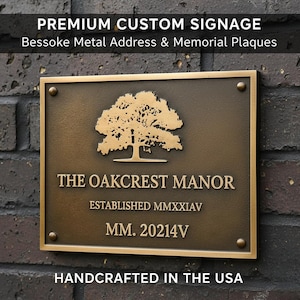 May include: A rectangular bronze metal plaque with the text "PREMIUM CUSTOM SIGNAGE" and "Bessoke Metal Address & Memorial Plaques". The plaque features a tree design and the words "THE OAKCREST MANOR", "ESTABLISHED MMXXIAV", and "MM. 20214V". The text "HANDCRAFTED IN THE USA" is also present.
