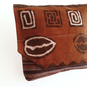 May include: A brown fabric pouch with a geometric pattern in white and brown. The pouch is made of a thick, textured fabric and has a flap closure.