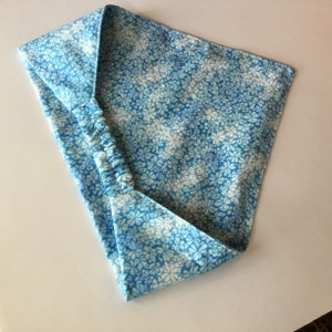 May include: A light blue headband with a white floral pattern. The headband has an elastic band for a comfortable fit.