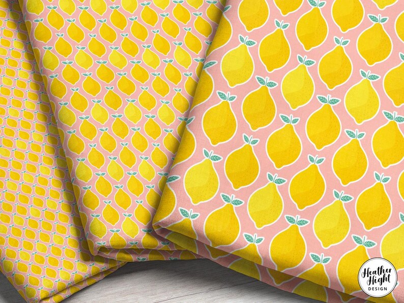 three folded fabric print scales featuring yellow geometric lemon illustrations with white borders and a pink background.