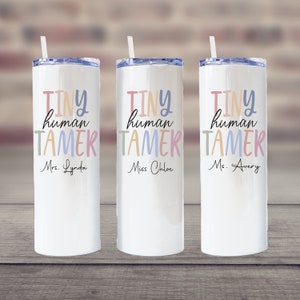 May include: Three white stainless steel tumblers with colorful text that reads "Tiny human tamer" and the names "Mrs. Lynda", "Miss Chloe", and "Ms. Avery".
