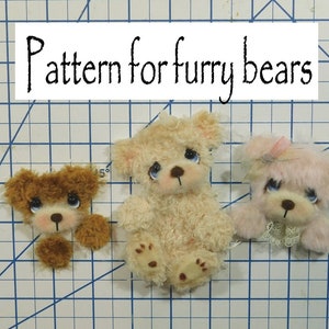 May include: Three small furry teddy bears, one brown, one cream, and one pink, with blue eyes and black noses. The bears are arranged on a blue and white grid background. The text "Pattern for furry bears" is written in black on a white rectangle above the bears.