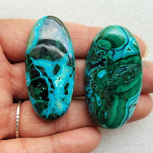 Op de afbeelding: Twee ovale, groene en blauwe chrysocolla cabochons met een marmerpatroon. De cabochons zijn glad en gepolijst.