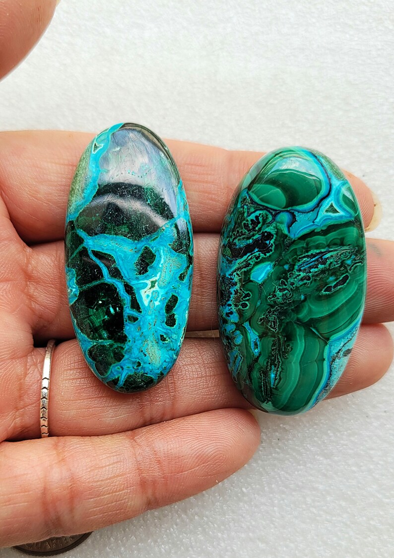 Op de afbeelding: Twee ovale, groene en blauwe chrysocolla cabochons met een marmerpatroon. De cabochons zijn glad en gepolijst.
