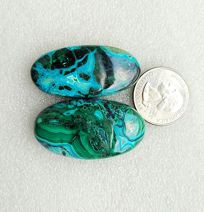 Op de afbeelding: Twee ovale turquoise en groene edelsteen cabochons. De stenen zijn ongeveer zo groot als een Amerikaanse kwart.