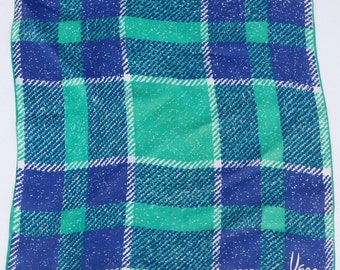 May include: A green and blue plaid patterned silk scarf with the word "Usma" in the bottom right corner.