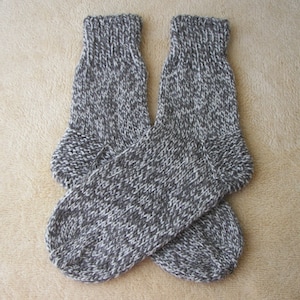 May include: A pair of gray and white knitted socks. The socks are made of a soft, warm yarn and have a textured knit.