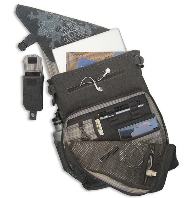 May include: A gray canvas messenger bag with a laptop, water bottle, phone, and other accessories inside. The bag has a zippered pocket and a mesh pocket. The bag is open and the contents are visible.