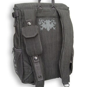 May include: A gray canvas backpack with a mesh pocket on the side and a large pocket on the front. The backpack has adjustable straps and a top handle. The back of the backpack features a gray embroidered design.