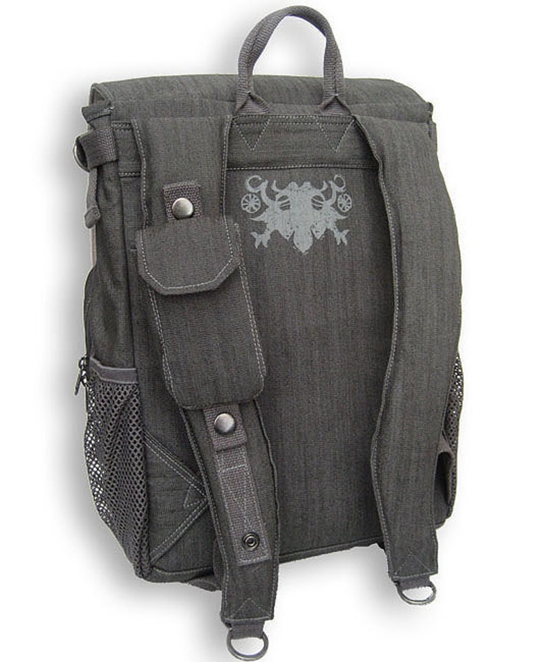 May include: A gray canvas backpack with a mesh pocket on the side and a large pocket on the front. The backpack has adjustable straps and a top handle. The back of the backpack features a gray embroidered design.