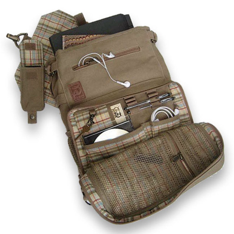 Peut inclure: Sacoche messager en toile beige avec plusieurs compartiments, dont une poche avant avec doublure en filet. Le sac pr&eacute;sente une doublure &agrave; carreaux et comprend une petite pochette lat&eacute;rale. Il contient un CD, des stylos et une tablette.