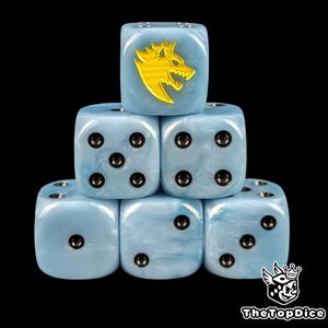 May include: Six light blue dice with a marbled effect, stacked against a black background. One die features a gold wolf emblem. The dice have black pips. The logo "TheTopDice" is in the bottom right corner.