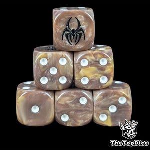 May include: Six brown and gold marbled dice with white pips are stacked against a black background. One die has a black spider emblem. The dice are for tabletop games. The dice are in a stack.