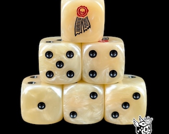 Puede incluir: Una pila de seis dados de color marfil con puntos negros. Un dado presenta un diseño de calavera y cinta roja. Los dados están dispuestos en forma de pirámide sobre un fondo negro. Estos dados son para juegos de mesa.