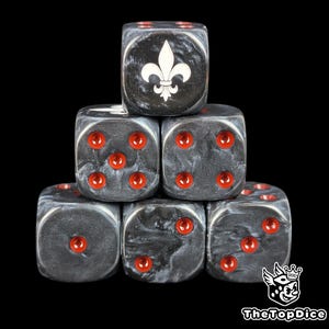 May include: Six dice with a black and white marbled pattern, stacked. Each die has red pips and a white fleur-de-lis symbol on one face. The dice are arranged in a pyramid shape against a black backdrop.