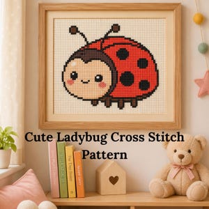 May include: A framed cross-stitch pattern of a cute ladybug with a smiling face, red shell, and black spots. The text "Cute Ladybug Cross Stitch Pattern" is below the frame. The frame is made of light brown wood.