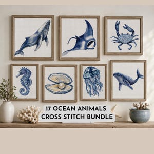Puede incluir: Una colección de siete obras de punto de cruz enmarcadas con vida marina azul, incluyendo una ballena, raya, cangrejo, caballito de mar, ostra con perla y medusa. El texto 17 OCEAN ANIMALS CROSS STITCH BUNDLE se muestra en el centro.