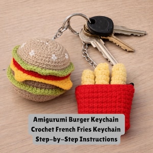 May include: Crocheted burger and french fries keychains. The burger has a tan bun, green lettuce, red tomato, and yellow cheese. The french fries are yellow and in a red container. The keychains are attached to a silver keyring with keys.