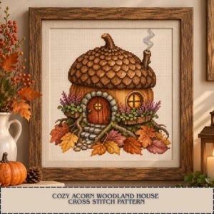 May include: A framed cross stitch pattern featuring an acorn-shaped house with a textured brown cap, a wooden door, and a chimney with smoke. The house is surrounded by purple flowers, green foliage, and colorful autumn leaves on the ground.