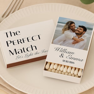May include: A white matchbox with the text "The PERFECT Match" and "Let's Light the Fire". The open matchbox displays a photo of a couple and the names "William & Emma" with the date "12/03/2025".