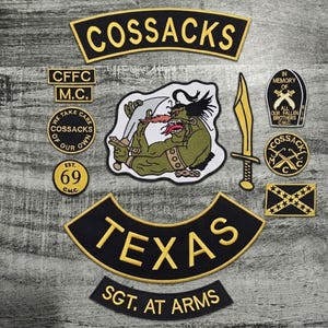 May include: A collection of embroidered patches with various designs and text. The patches include the word "COSSACKS" in a curved banner, "TEXAS", and "SGT. AT ARMS". Other patches feature a green monster with swords and the text "IN MEMORY OF".