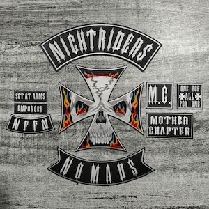 Könnte beinhalten: Eine Sammlung von schwarz-weißen gestickten Aufnähern mit verschiedenen Designs und Texten. Die Aufnäher zeigen ein Totenkopfkreuz, die Wörter "NIGHTRIDERS", "NOMADS", "M.C." und andere Phrasen. Die Aufnäher sind auf grauem Hintergrund.