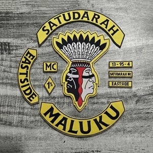 May include: A collection of yellow and black patches with text and graphics. The patches include the words "SATUDARAH", "EASTSIDE", and "MALUKU". A central patch features two faces, one black and one white, with a feathered headdress. Additional patches read "MC", "1%", "13-95-4", "SATUDARAH MC", and "EASTSIDE".