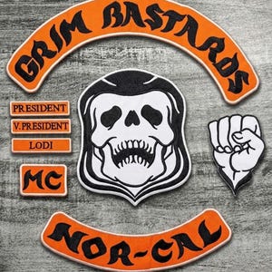 Op de afbeelding: Een verzameling geborduurde patches met een biker-thema. De patches bevatten een schedel, een vuist en tekst zoals "GRIM BASTARDS", "NOR-CAL", "PRESIDENT", "V.PRESIDENT", "LODI" en "MC". De patches zijn voornamelijk oranje en zwart.