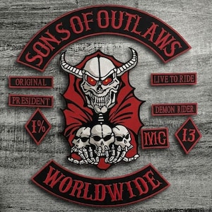 Puede incluir: Un conjunto de parches bordados con temática motera. El parche central presenta una calavera con cuernos y ojos rojos, rodeada por una capa roja. Otros parches incluyen textos como "SONS OF OUTLAWS", "LIVE TO RIDE" y "WORLDWIDE".