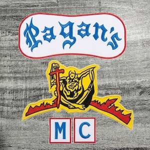 Puede incluir: Parches bordados con el texto "Pagan's" en letras góticas azules sobre fondo blanco con borde rojo. Debajo, un parche amarillo con una figura sosteniendo una espada y una pancarta. Dos parches más pequeños leen "M" y "C" en azul.