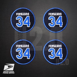 May include: Four circular patches with the name "FERNANDO" above the number "34" in white and blue. The patches have a navy blue background with a blue border. The United States Postal Service logo is in the lower left corner.