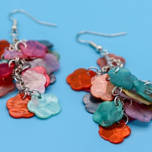 May include: A pair of dangle earrings featuring a silver chain and numerous colourful flower-shaped charms. The charms are in shades of red, pink, green, blue, and purple.