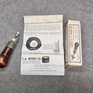 Puede incluir: Un punz&oacute;n de coser de cuero vintage con un mango de madera y una cabeza de metal. El punz&oacute;n est&aacute; empaquetado en una caja de cart&oacute;n blanca con texto negro que dice "C.A. Myers Co. 7007 N. Glenwood Ave. Chicago, Ill. 60626 U.S.A."