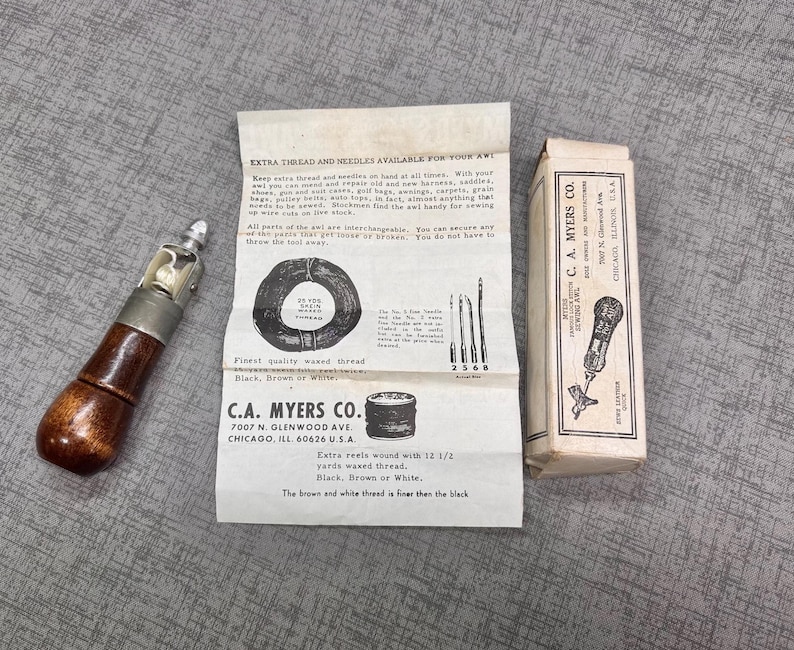 Puede incluir: Un punz&oacute;n de coser de cuero vintage con un mango de madera y una cabeza de metal. El punz&oacute;n est&aacute; empaquetado en una caja de cart&oacute;n blanca con texto negro que dice "C.A. Myers Co. 7007 N. Glenwood Ave. Chicago, Ill. 60626 U.S.A."