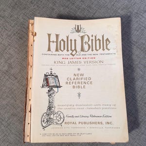Puede incluir: Una edición de la Santa Biblia con letras rojas, versión King James, con una nueva referencia clarificada. La portada presenta un soporte decorativo con un libro abierto y el texto "Venid a mí, todos los que estáis trabajados y cargados, y yo os haré descansar. Mateo 11:28."