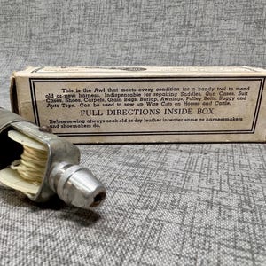Puede incluir: Un punz&oacute;n de coser de cuero vintage con mango de madera y aguja de metal. El punz&oacute;n est&aacute; en una caja de cart&oacute;n con el texto "This is the Awl that meets every condition for a handy tool to mend old or new harness. Indispensable for repairing Saddles, Gun Cases, Suit Cases, Shoes, Carpets, Grain Bags, Burlap, Awnings, Pulley Belts, Buggy and Auto Tops. Can be used to sew up Wire Cuts on Horses and Cattle. FULL DIRECTIONS INSIDE BOX Before sewing always soak old or dry leather in water same as harnessmakers and shoemakers do."