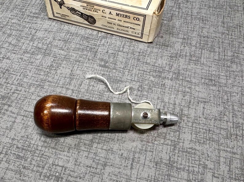 Puede incluir: Un punz&oacute;n de mango de madera marr&oacute;n con un carrete de metal y una aguja de metal. El punz&oacute;n se utiliza para coser cuero.