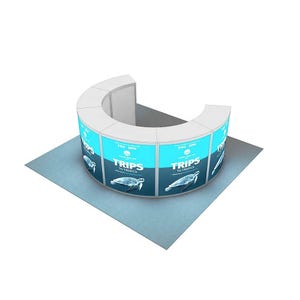 May include: A curved trade show booth with a light blue and white design. The booth features the text "TRIPS TO TROPICS" and an image of a sea turtle. The booth is on a gray surface.