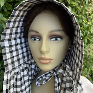 May include: A black and white gingham bonnet with a gathered ruffle around the face. The bonnet is tied at the neck with a matching ribbon.