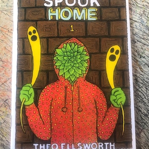 May include: A comic book cover with the title "SPOOK HOME" in white and yellow letters. The illustration features a figure in a red hoodie with a green leafy head, holding yellow ghost-shaped objects. The artist's name, "THEO ELLSWORTH," is at the bottom.