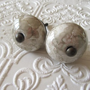 以下が含まれることがあります： クリーム色、ライトグレー、ダークグレーの3色の、まだら模様のマット仕上げのセラミックマグのセット。各マグはシンプルでミニマルなデザインで、丸みを帯びたハンドルが付いています。