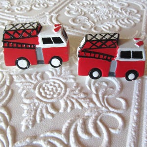 Pu&ograve; includere: Due miniature di autopompe rosse e bianche con dettagli neri. Ogni camion ha una scala, ruote nere e un tetto bianco. Lo sfondo &egrave; una superficie bianca strutturata.