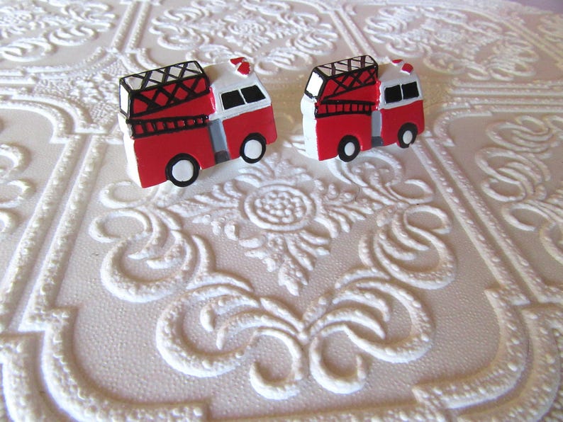 Pu&ograve; includere: Due orecchini a forma di camion dei pompieri rossi e bianchi con dettagli neri e bianchi. Gli orecchini sono repliche in miniatura di camion dei pompieri, con scale e sirene. Sfondo bianco strutturato.