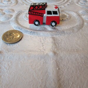 Pu&ograve; includere: Un piccolo camion dei pompieri rosso e bianco con ruote nere e una scala. Una moneta &egrave; accanto al giocattolo per il confronto delle dimensioni. Il camion dei pompieri &egrave; un oggetto di novit&agrave;.