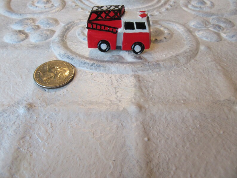 Pu&ograve; includere: Un piccolo camion dei pompieri rosso e bianco con ruote nere e una scala. Una moneta &egrave; accanto al giocattolo per il confronto delle dimensioni. Il camion dei pompieri &egrave; un oggetto di novit&agrave;.