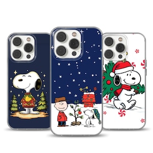 Op de afbeelding: Drie telefoonhoesjes met Snoopy en Charlie Brown in kerstscènes. De hoesjes hebben een donkerblauwe, witte en marineblauwe achtergrond. Snoopy draagt een kersttrui, een kerstmuts en een groen-rode sjaal.