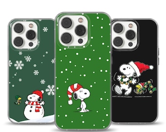 Può includere: Tre custodie per telefono con disegni natalizi di Snoopy. Una è verde scuro con fiocchi di neve e un pupazzo di neve Snoopy. Un'altra è verde con Snoopy con un cappello da Babbo Natale. La terza è nera con Snoopy con un cappello da Babbo Natale e una ghirlanda.